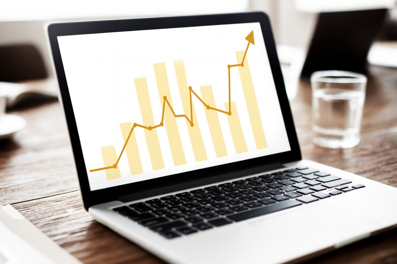Laptop z wykresem słupkowym i linią trendu wzrostowego