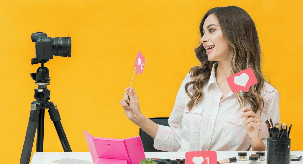 Influencerka przy biurku z kamerą, kosmetykami i ikonami polubień