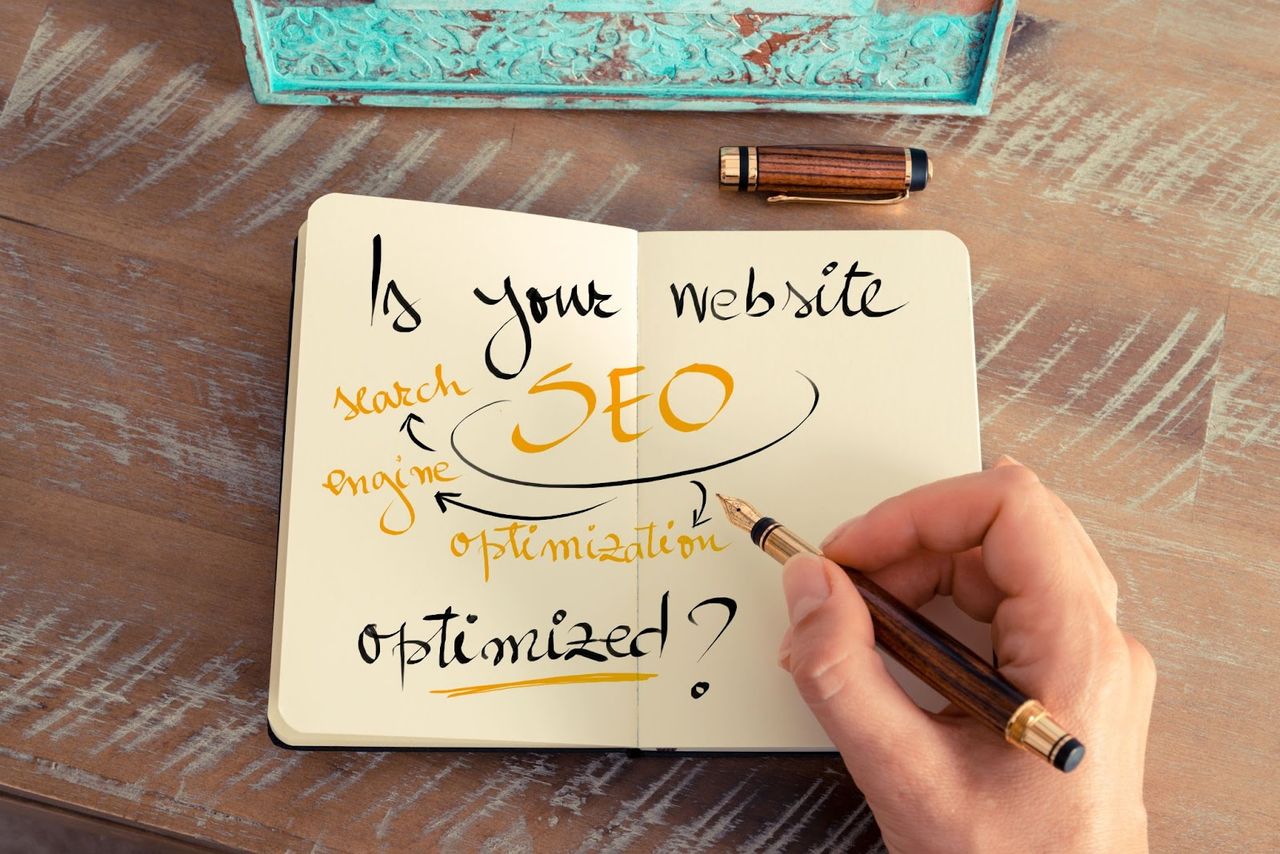 Notatnik z odręcznym napisem Is your website SEO optimized na drewnianym biurku