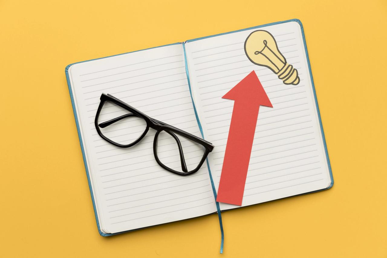 Otwarty notes z czerwoną strzałką wzrostu i rysunkiem żarówki na żółtym tle