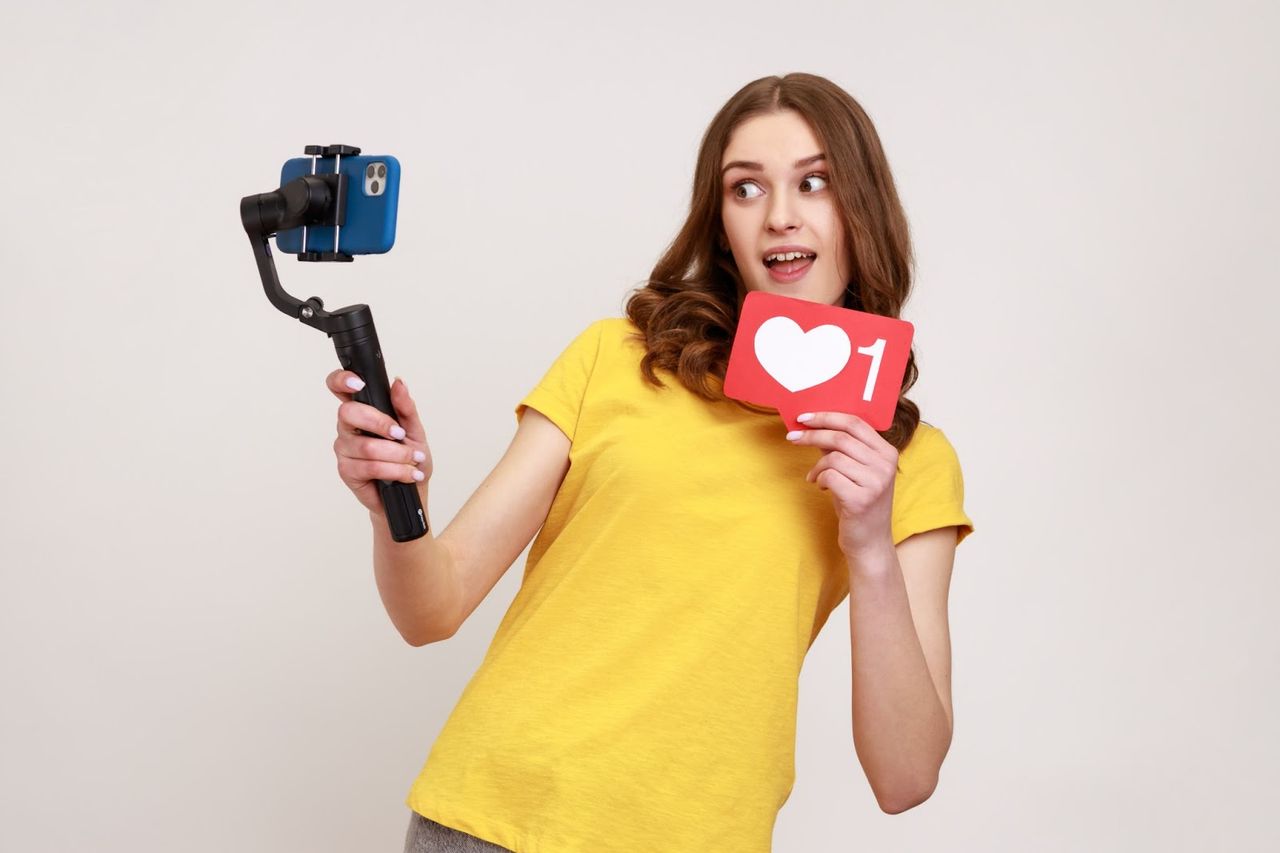 Dziewczyna z gimbalem i tabliczką serduszka – nagrywanie treści social media