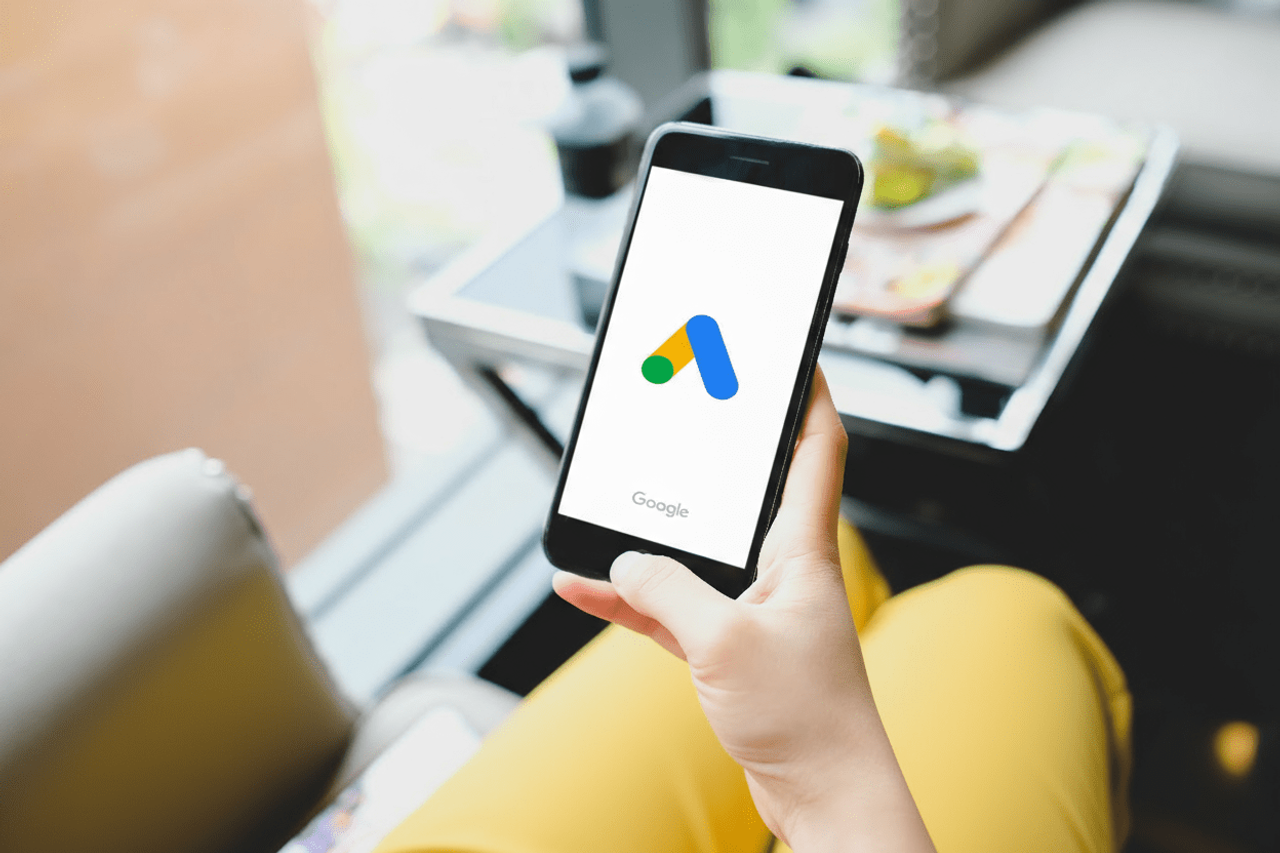 Kobieta trzymająca smartfon z logo Google Ads na ekranie