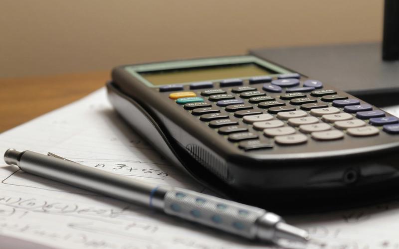A student study setup with textbooks, a pen and a calculator for calculating GPA