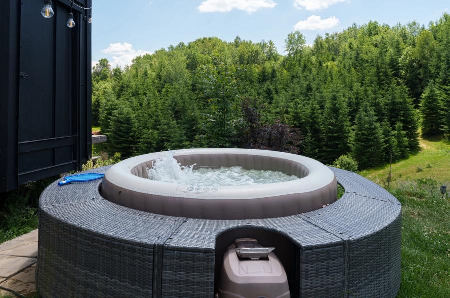 The Dyno tiny house with a hot tub on the terrace and a forest view