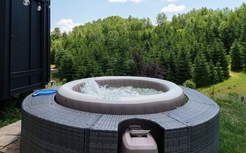 Jacuzzi privat pe terasa tiny house-ului Dyno, cu priveliște spre pădurea de pini