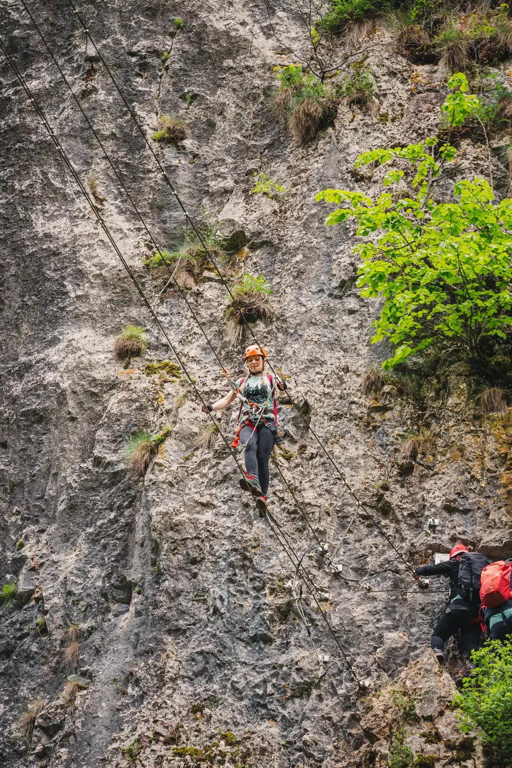 Climbers on a vertical wall on the via ferrata route at Șuncuiuș