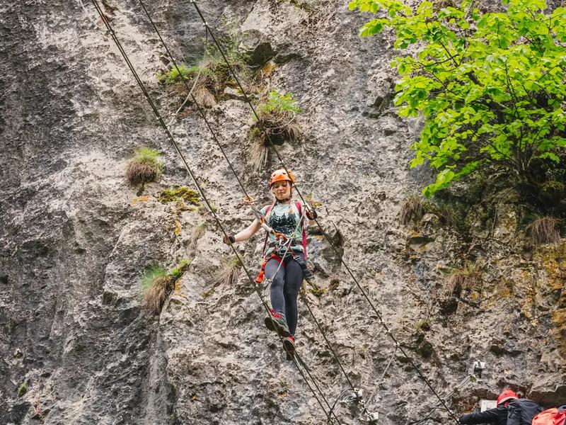 The vertical sections are secured with a continuous cable Climbers on a vertical wall on the via ferrata route at Șuncuiuș