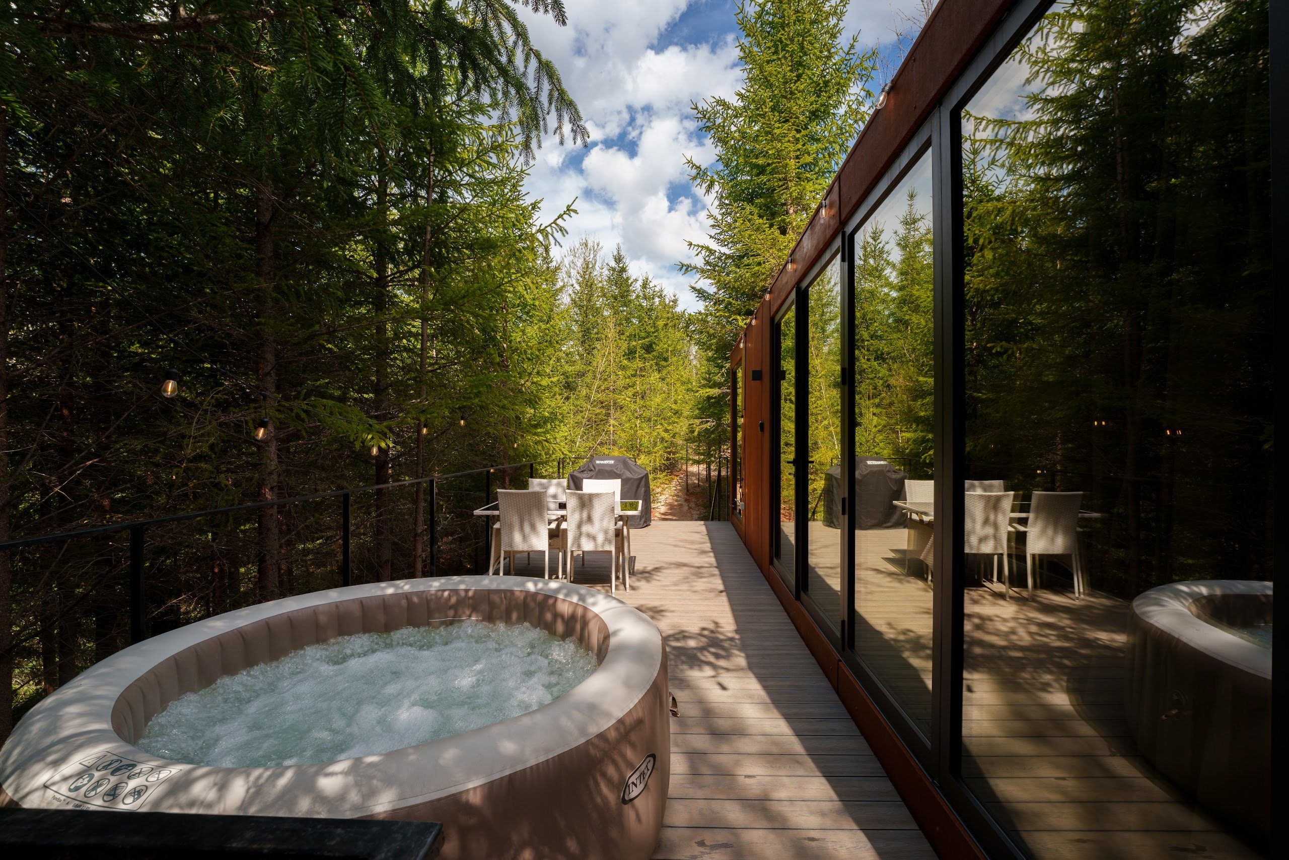 Heated hot tub on the deck of the Luna tiny house, surrounded by fir trees