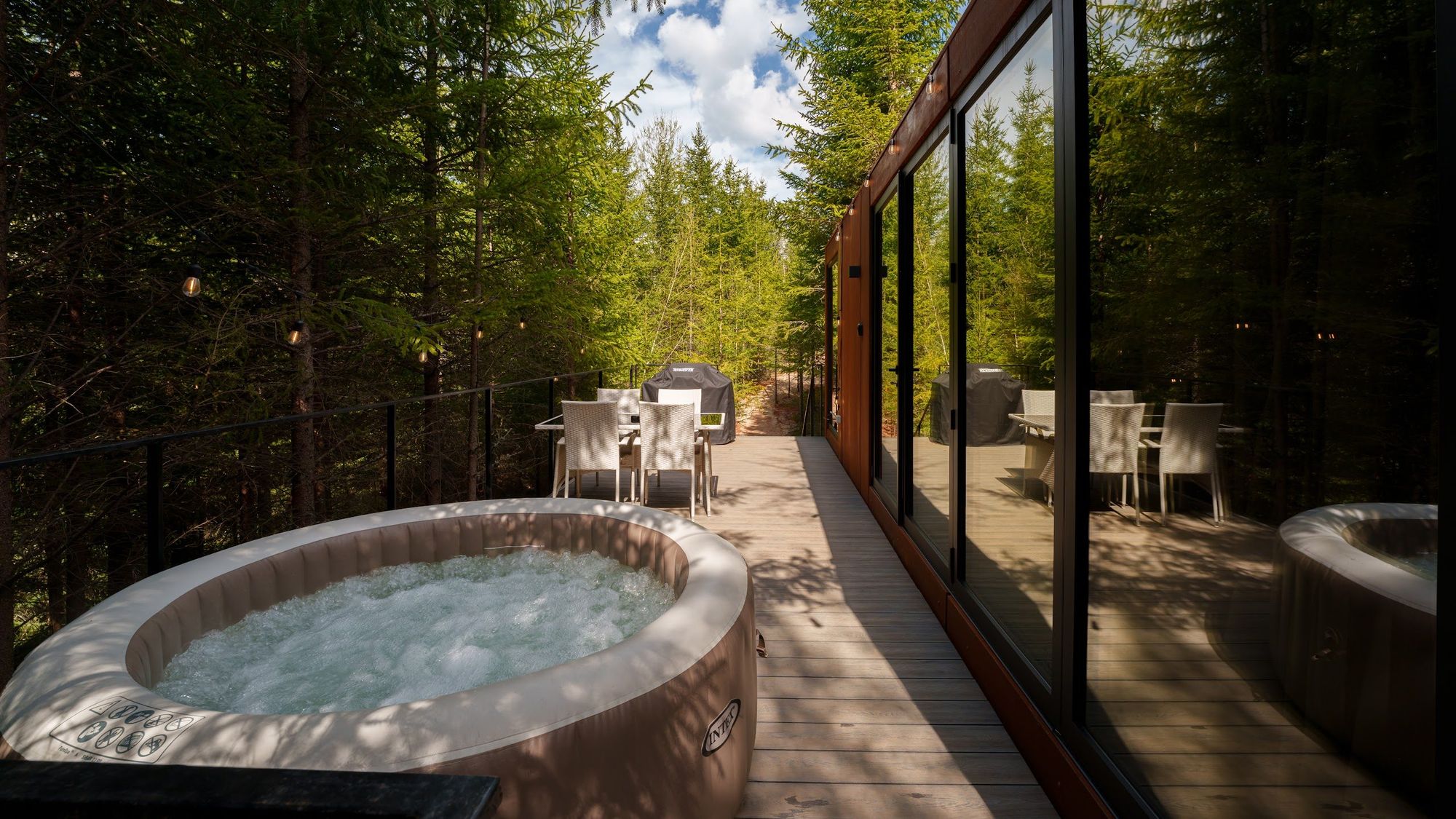Jacuzzi încălzit pe terasa tiny house-ului Luna, înconjurat de brazi