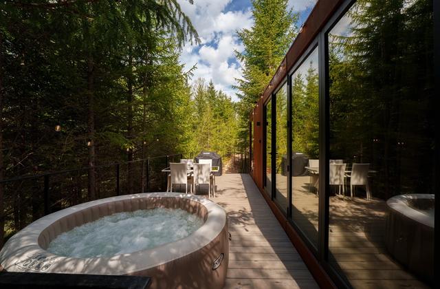 Jacuzzi încălzit pe terasa tiny house-ului Luna, înconjurat de brazi