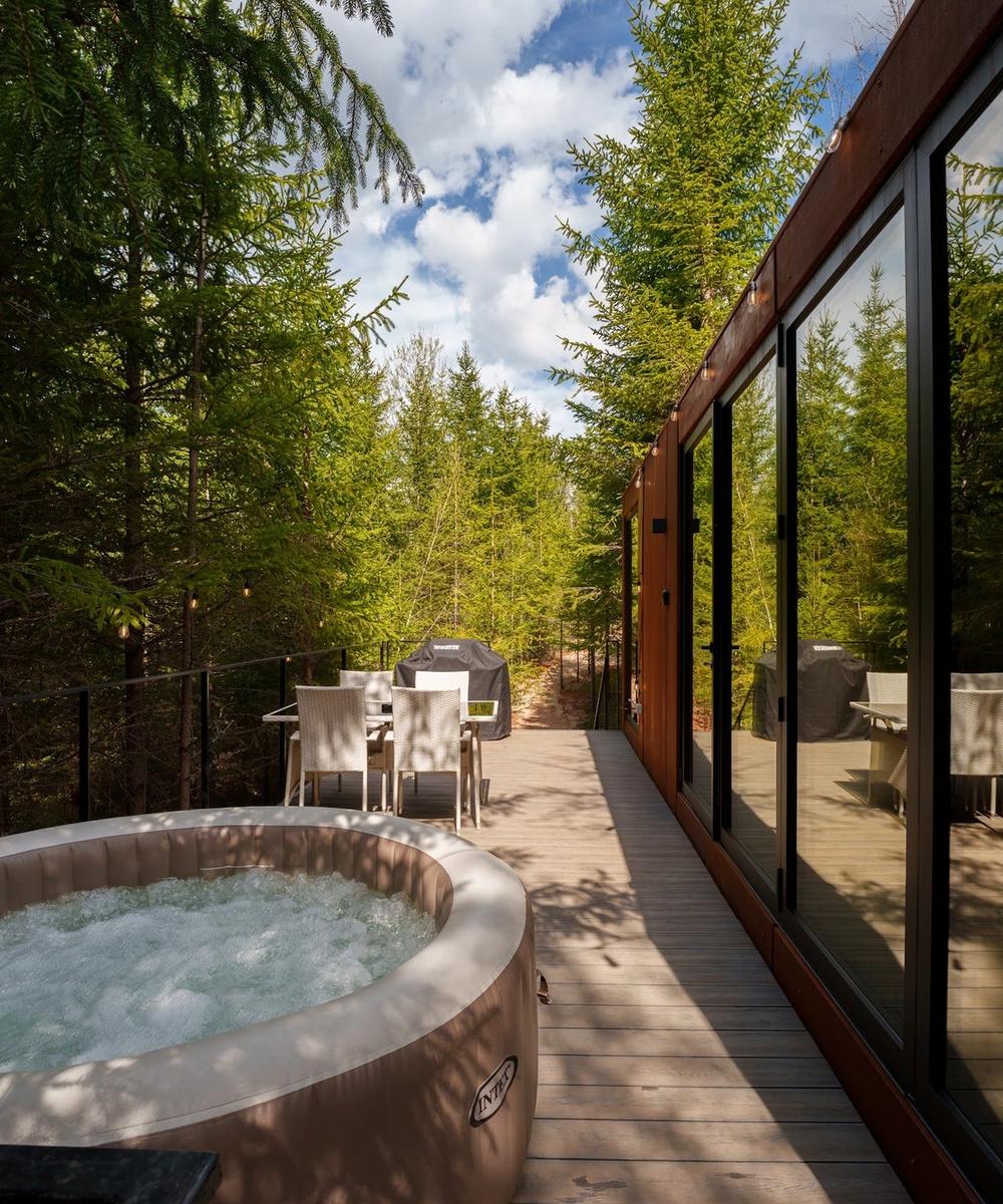 Jacuzzi încălzit pe terasă Jacuzzi încălzit pe terasa tiny house-ului Luna, înconjurat de brazi