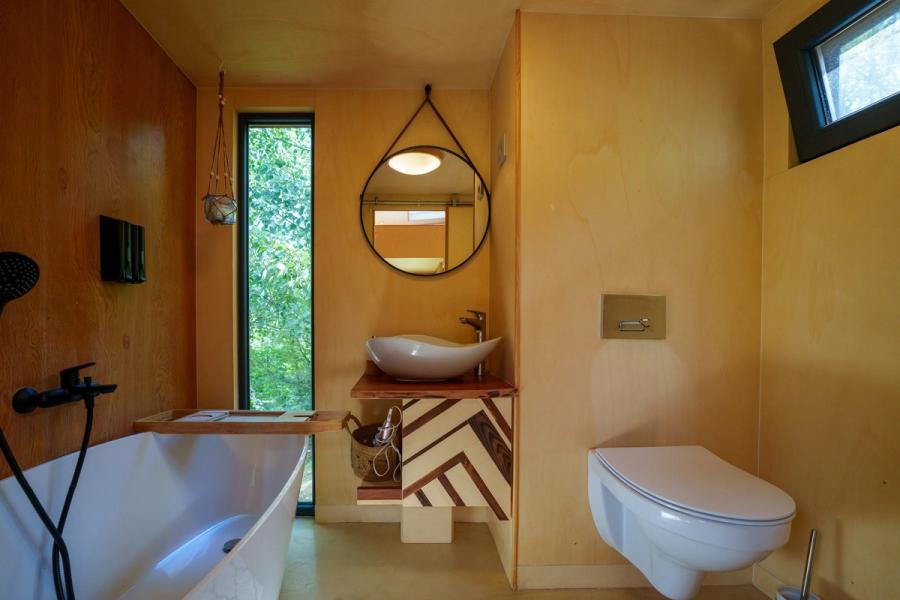 Bathroom with a tub next to the window overlooking the forest, in the Hypo tiny house