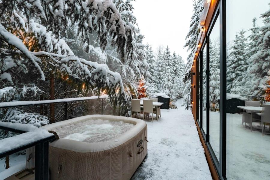 Steaming outdoor hot tub among fir trees in winter at the Luna tiny house