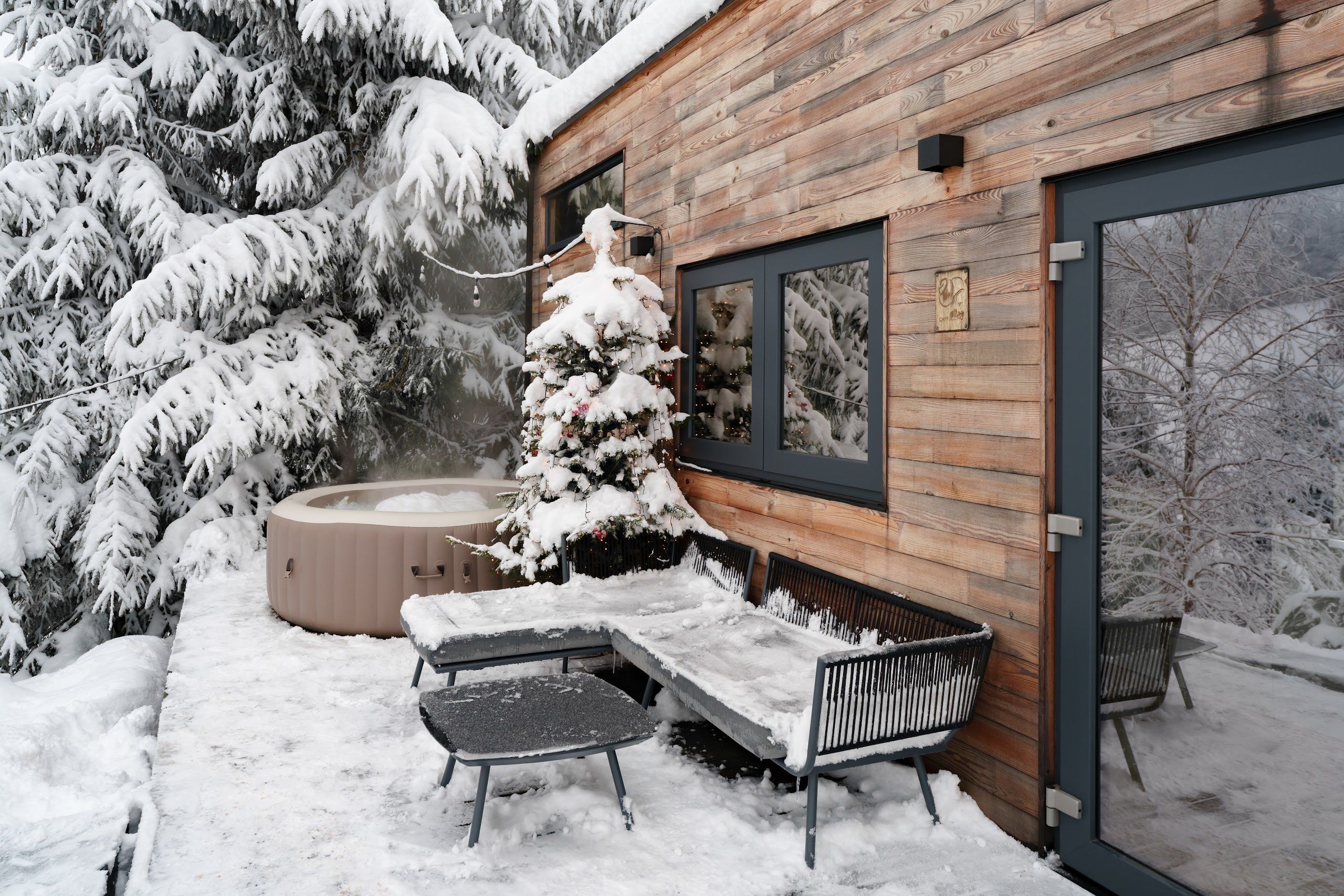 Warm hot tub among fir trees in winter at the Cappuccino tiny house, Coniferis Retreat