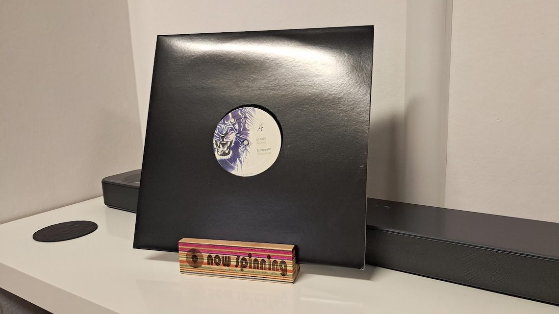 A handmade vinyl cover stand, combining recycled skateboard decks and walnut wood to display the sleeve of the record currently playing.