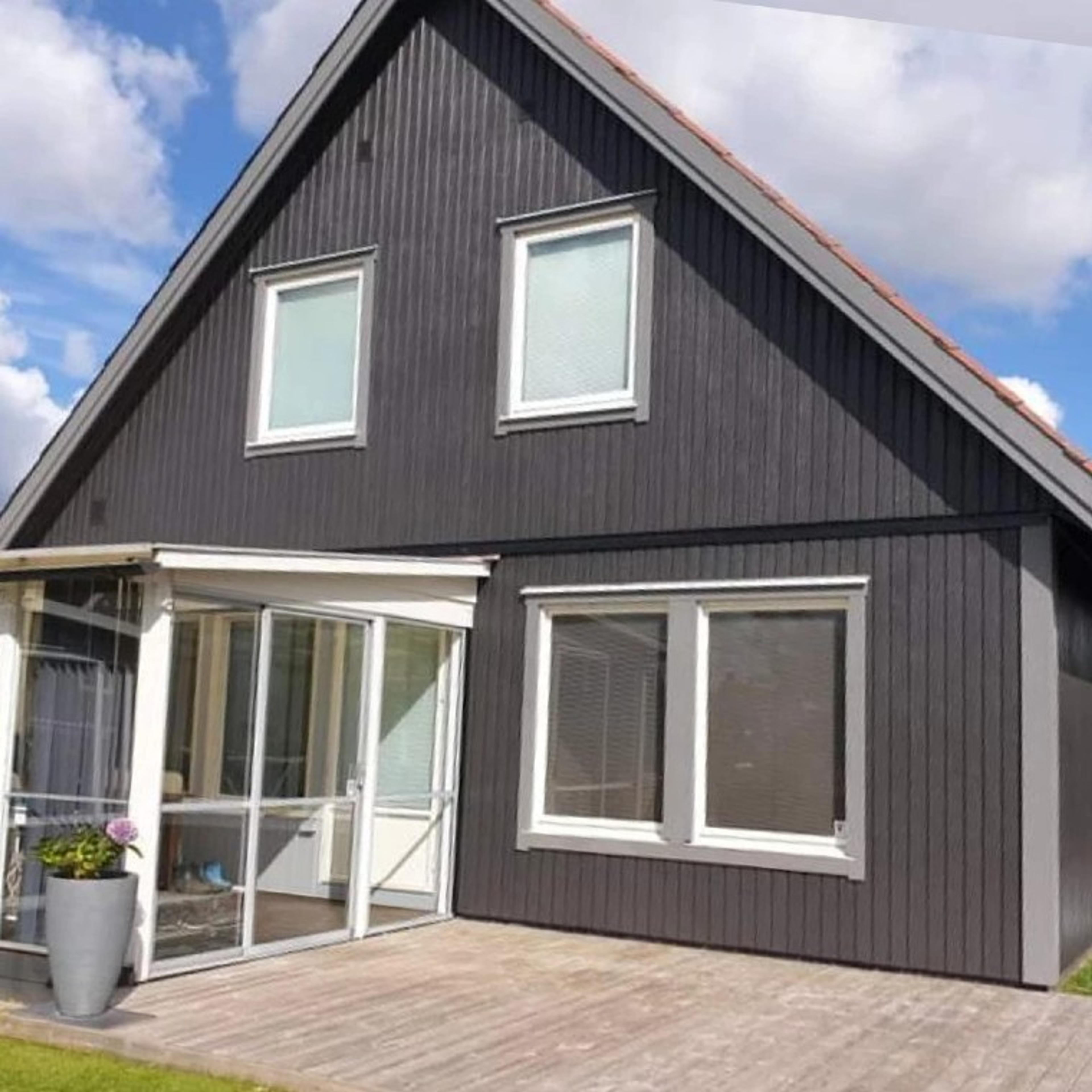 AH Bygg har monterat gråa fönster i ett svart hus, snygg kontrast