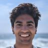 a young man with a beard is smiling for the camera on the beach .