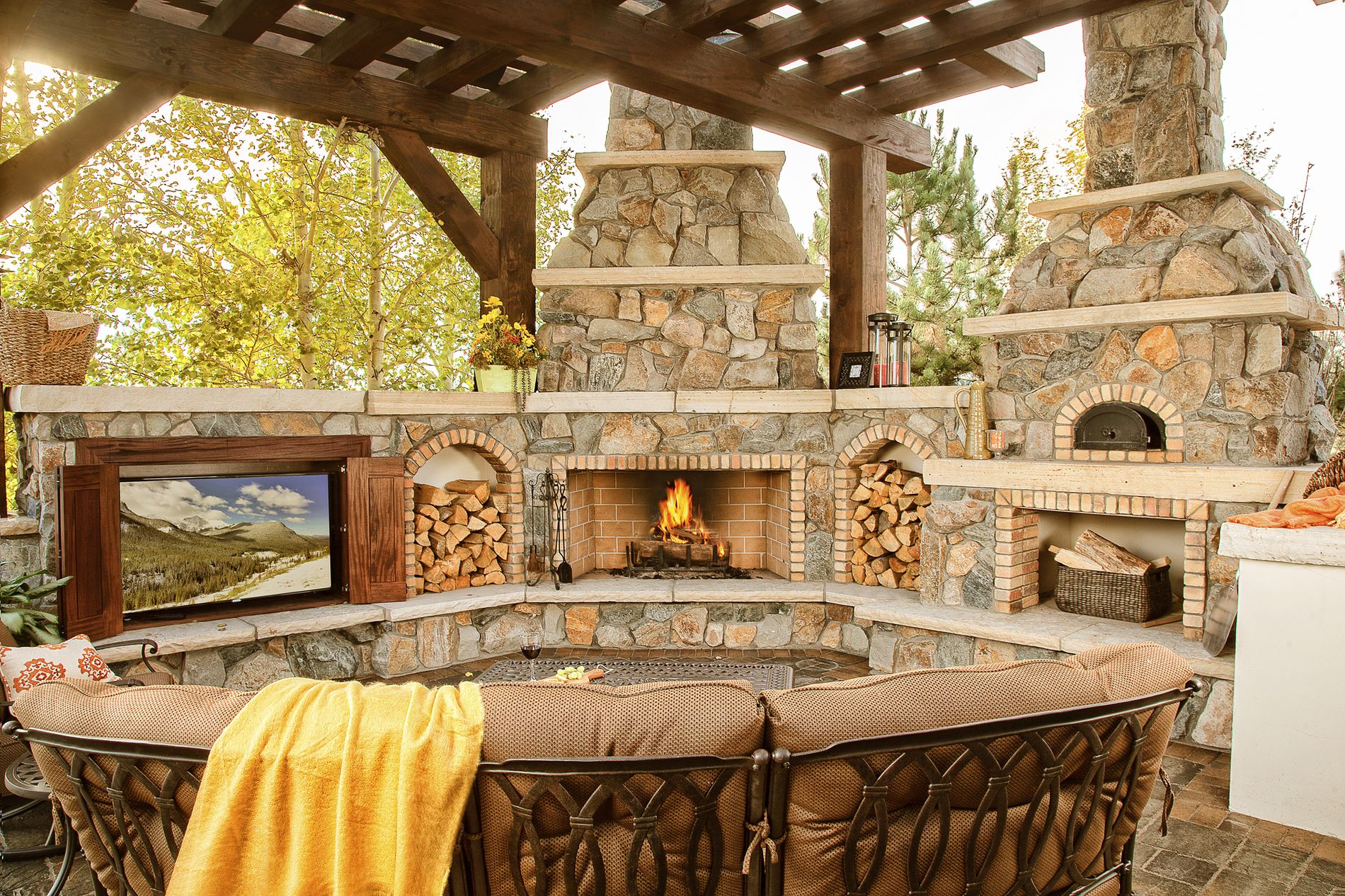 Wood burning outdoor fireplace with television cabinet and pizza oven