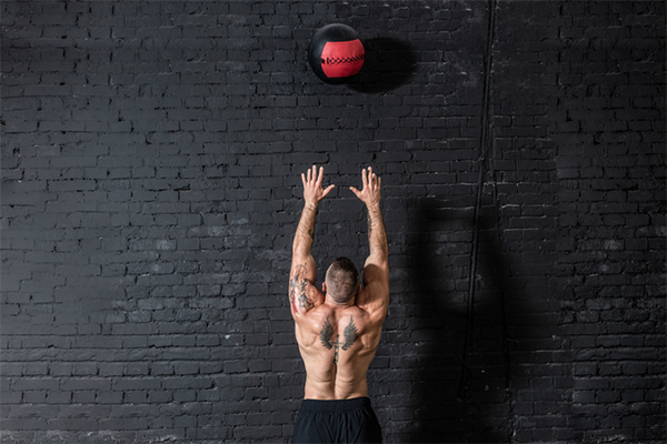 man throwing medicine ball up wall | wall ball exercises