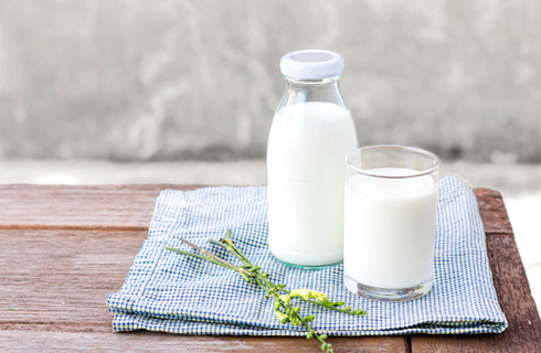 glass of milk on tablecloth | foods that help with muscle cramps