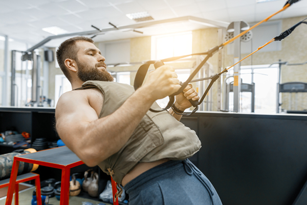 man using suspension trainer | weighted vest