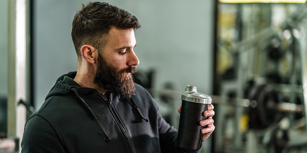 man looking at shaker bottle | should I take creatine on off days