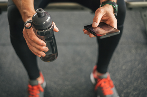 person in gym holding water bottle and phone | how to improve focus