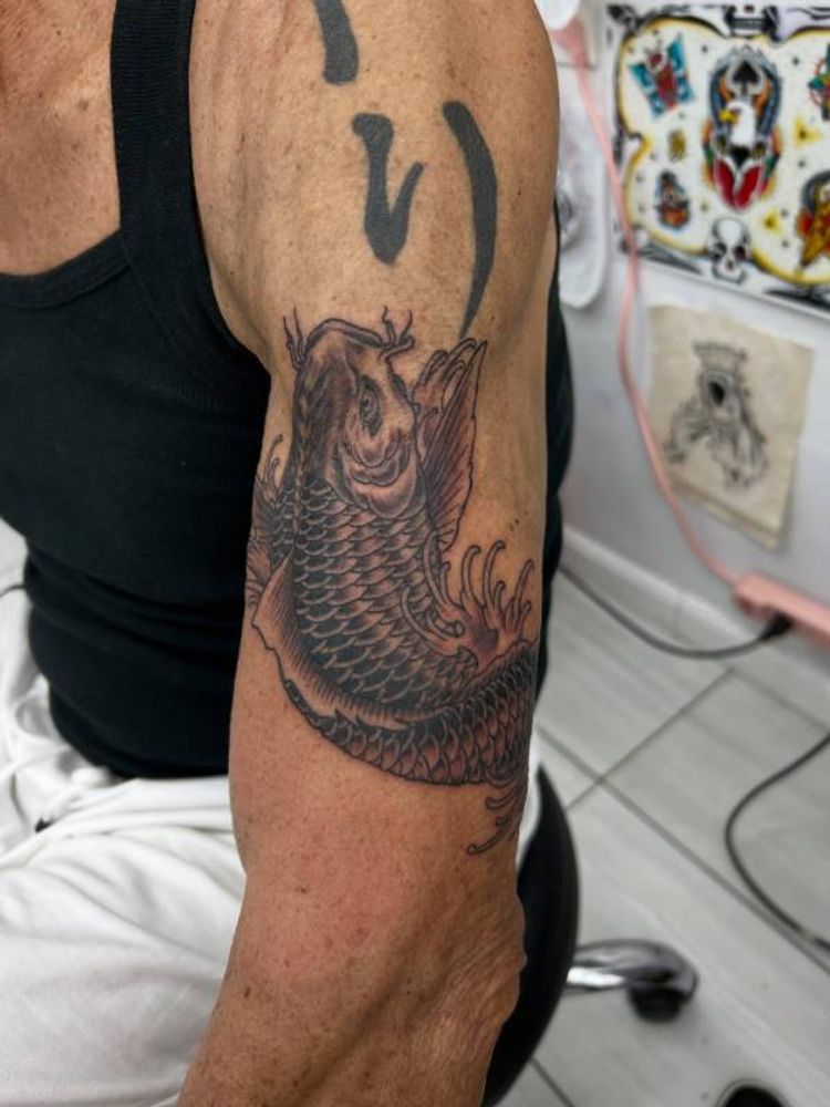 Black and grey koi fish tattoo on upper arm