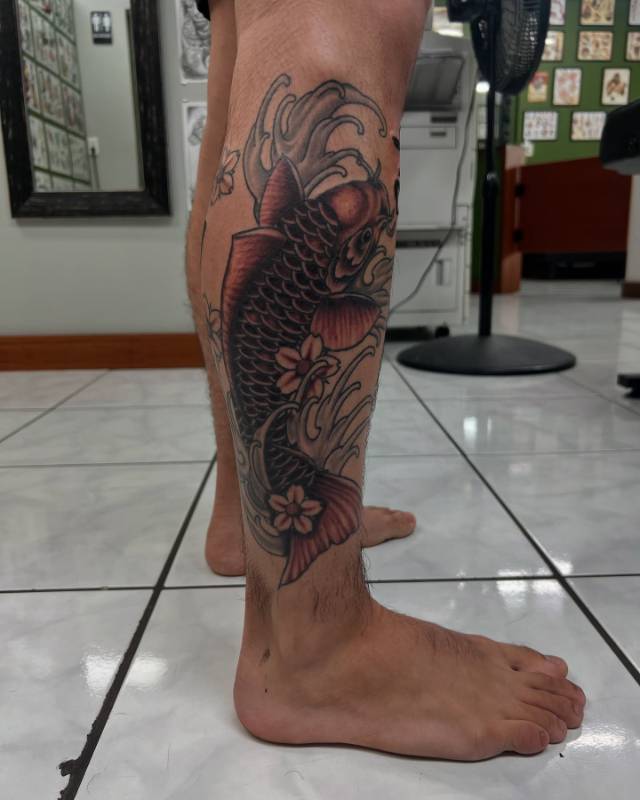 Colorful koi fish tattoo on calf with wave elements