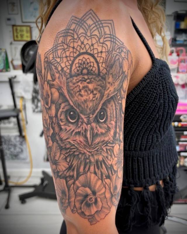 Black and grey ornamental owl tattoo on upper arm