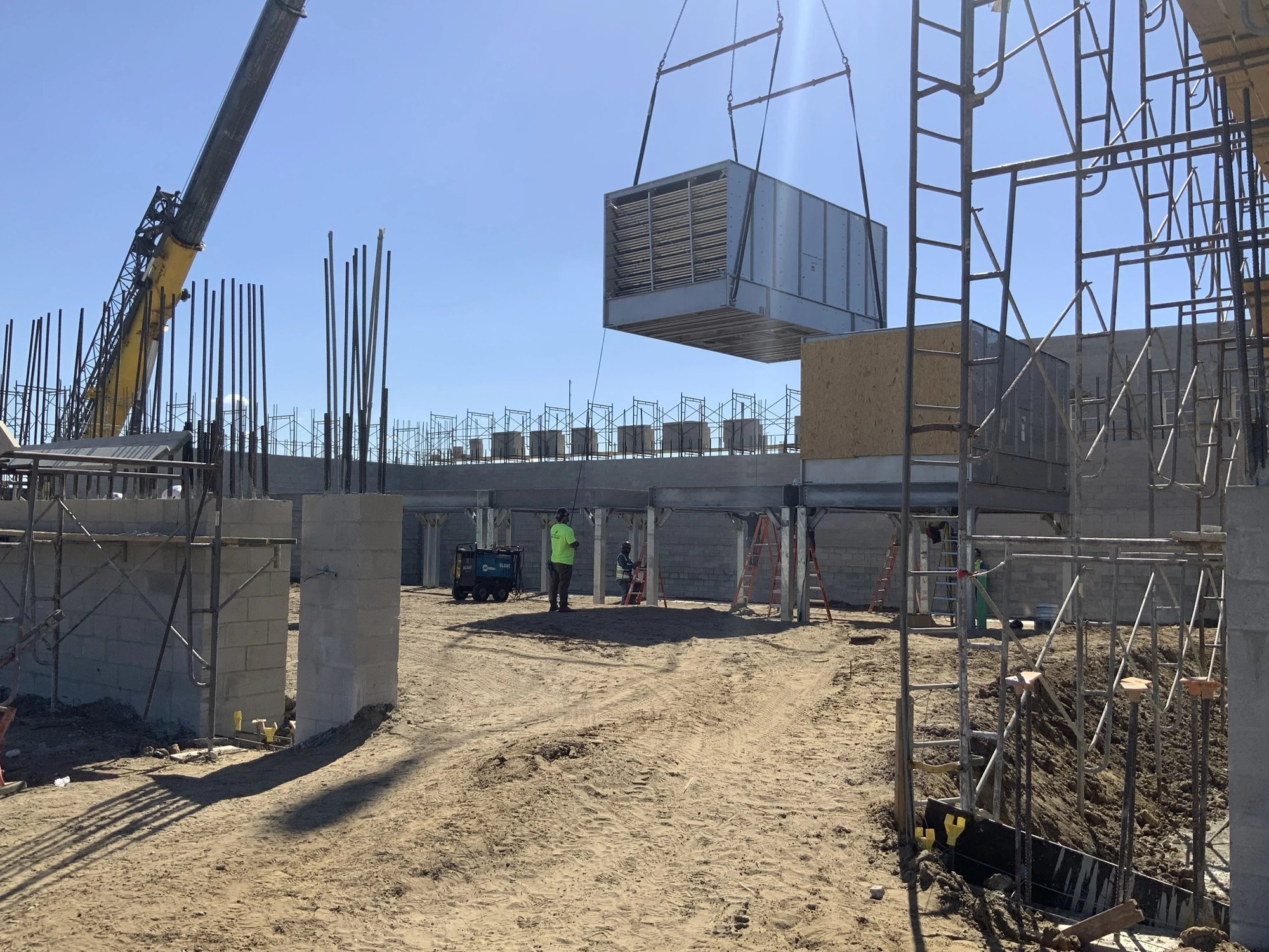 A crane lifting mechanical equipment into position at a building under construction at BayCare Manatee