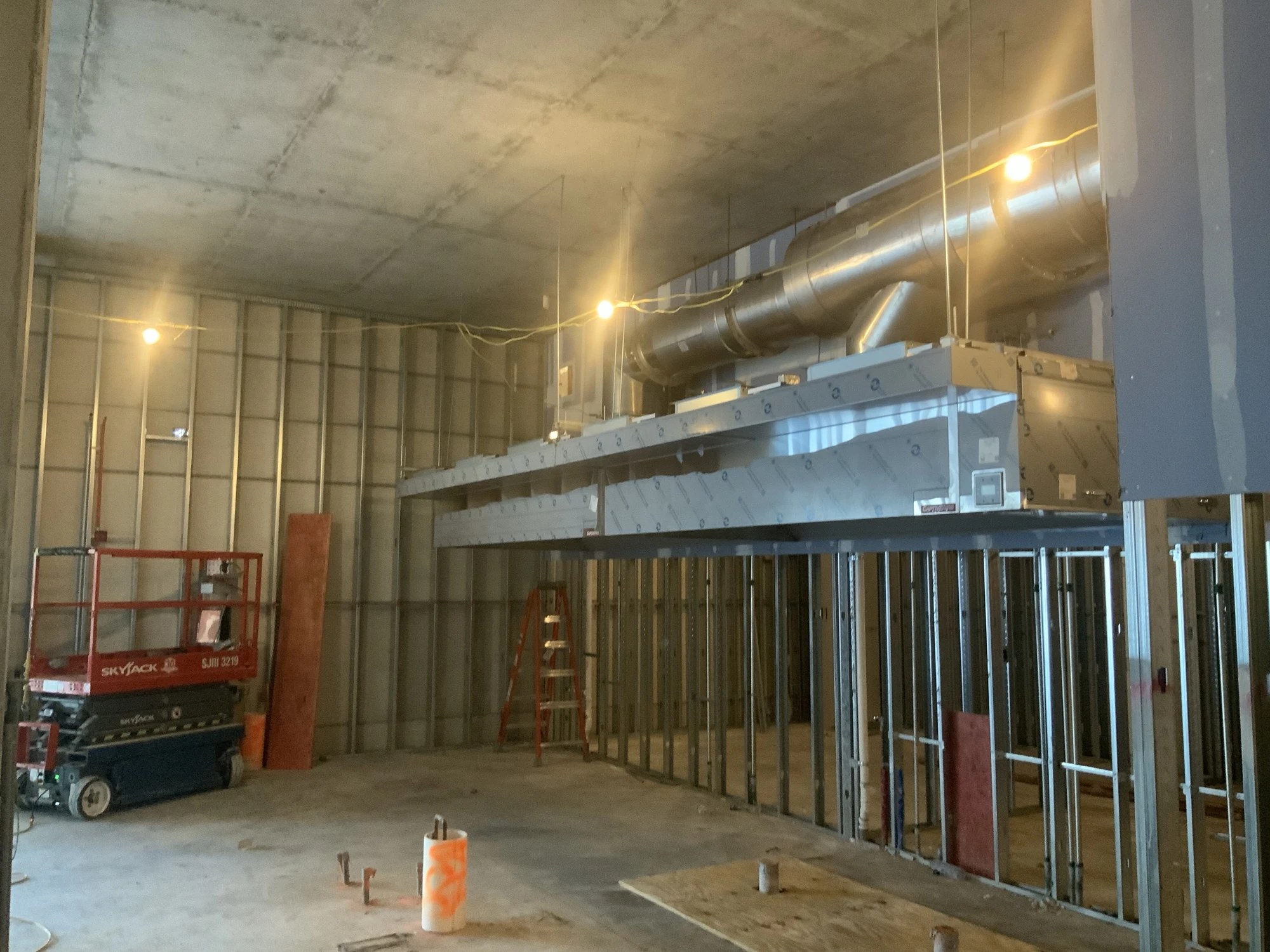 Overhead ductwork and a suspended mechanical unit in an unfinished interior at BayCare Manatee