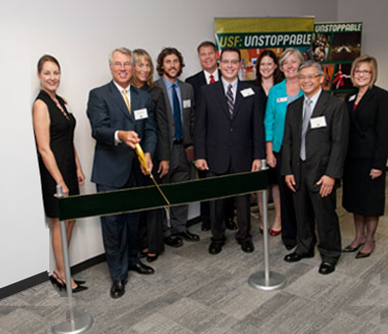 USF Health ALS Clinic ribbon-cutting group, with the ribbon and ceremonial scissors