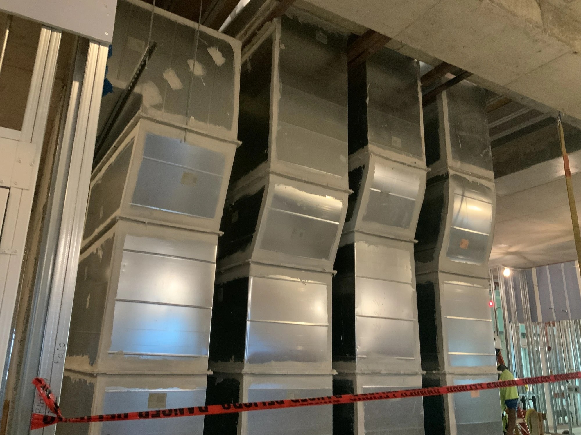 Multiple formed sheet metal ductwork runs installed below a concrete ceiling at BayCare Manatee