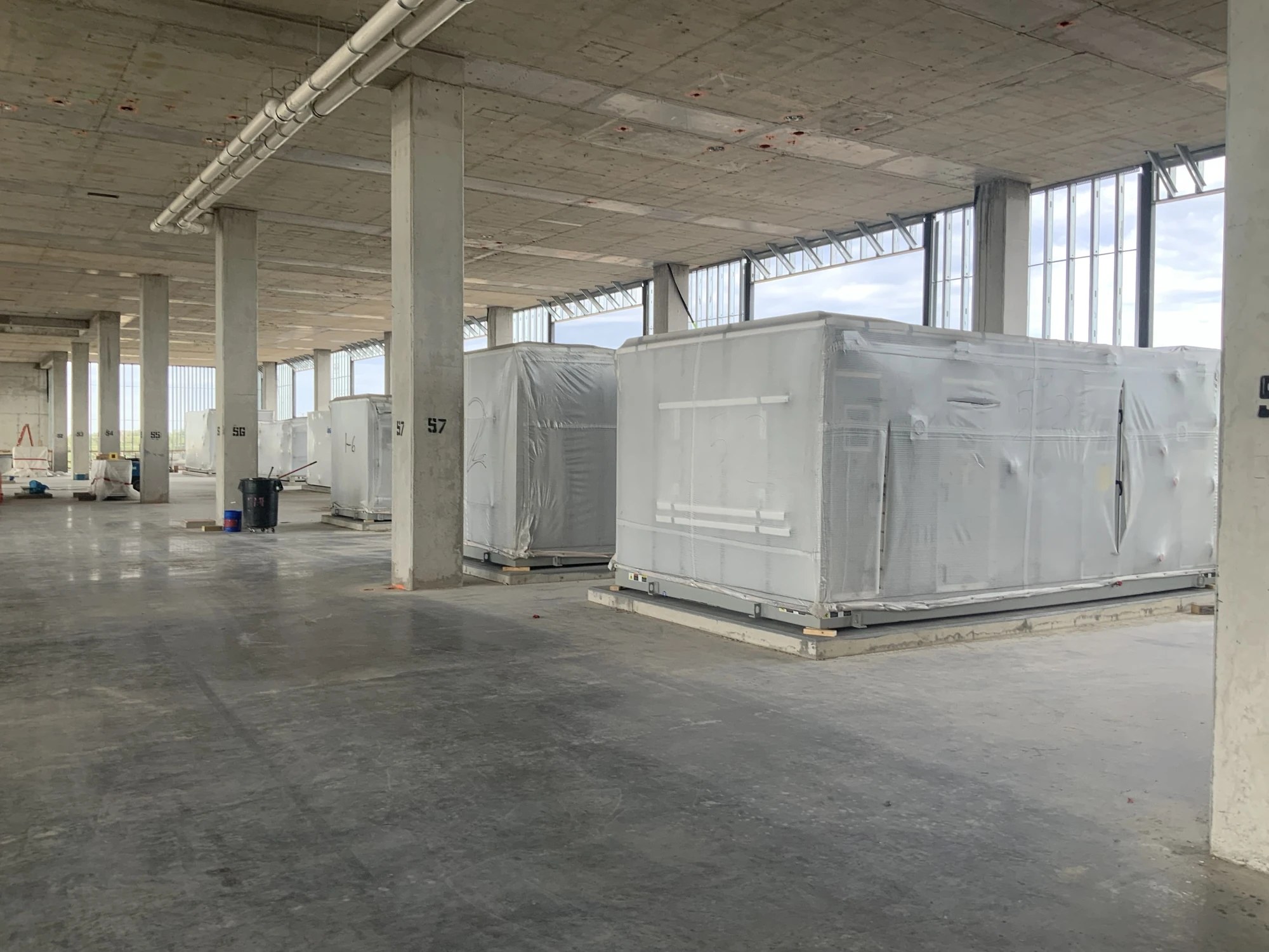 Wrapped mechanical equipment and overhead ductwork in an unfinished building interior at BayCare Manatee