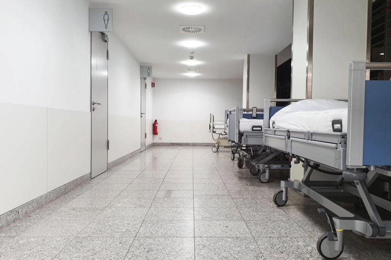 Wad hospital dengan barisan katil pesakit yang menggambarkan kesesakan sistem kesihatan awam