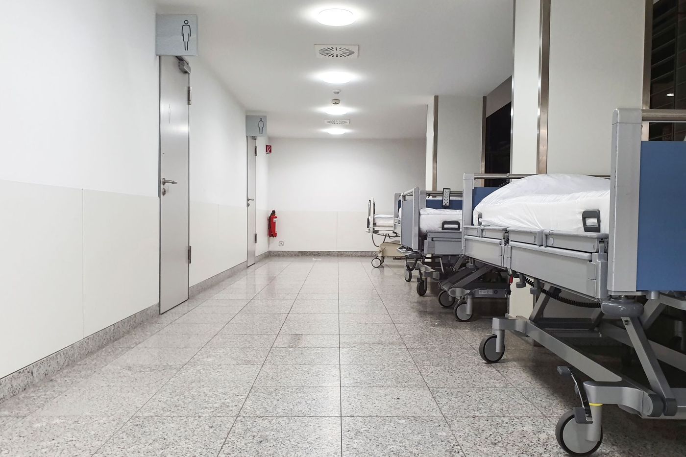 Wad hospital dengan barisan katil pesakit yang menggambarkan kesesakan sistem kesihatan awam
