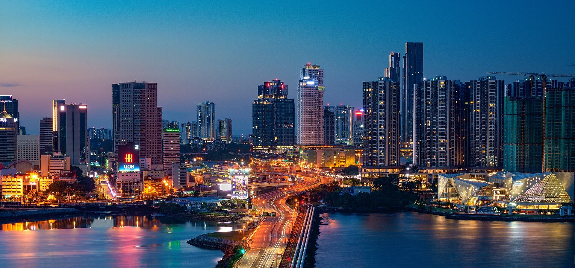 Panorama pusat bandar Johor Bahru pada waktu malam dengan bangunan pencakar langit dan Tambak Johor