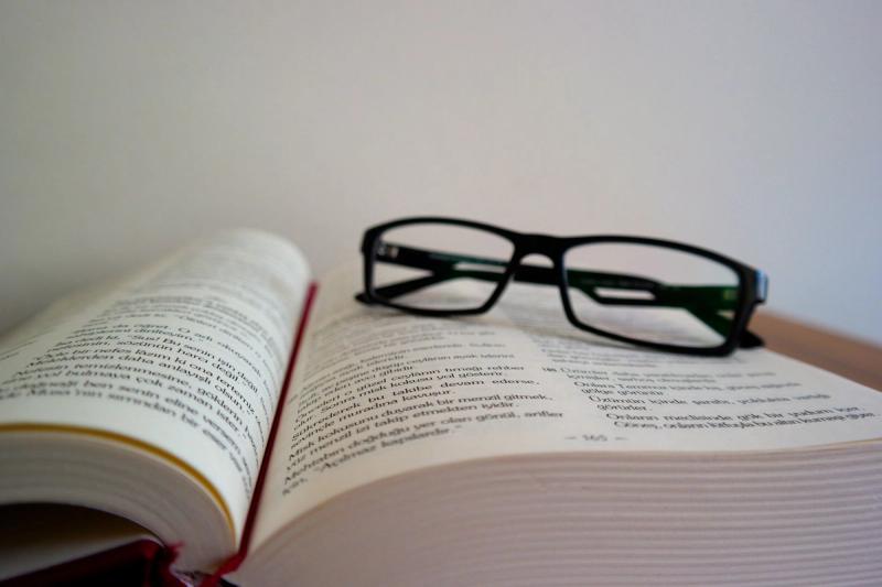 Buku terbuka di atas meja sebagai lambang pembacaan dan pembelajaran bahasa