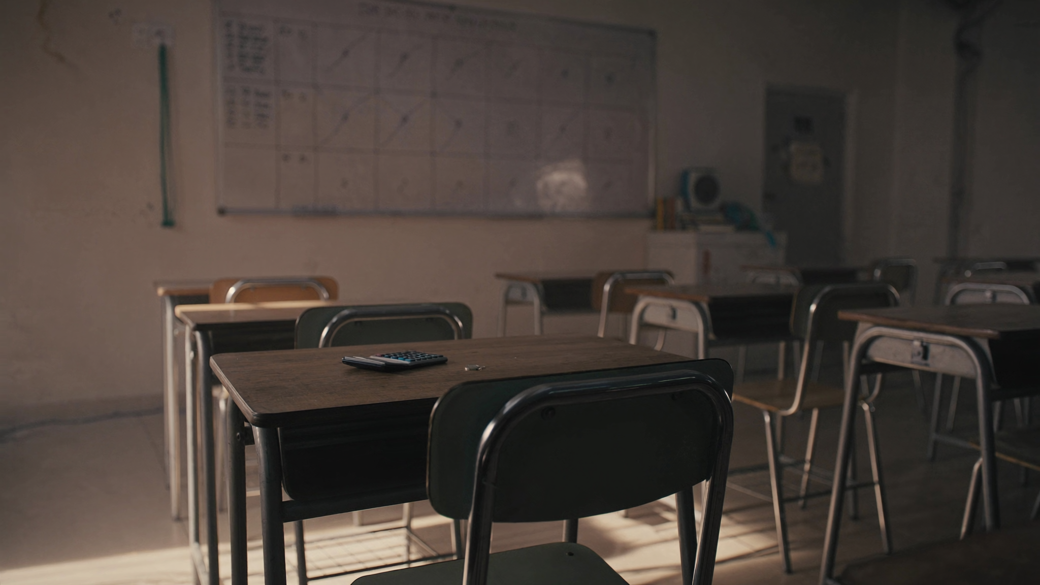 Bilik darjah sekolah yang kosong dengan papan putih dan kalkulator di atas meja murid