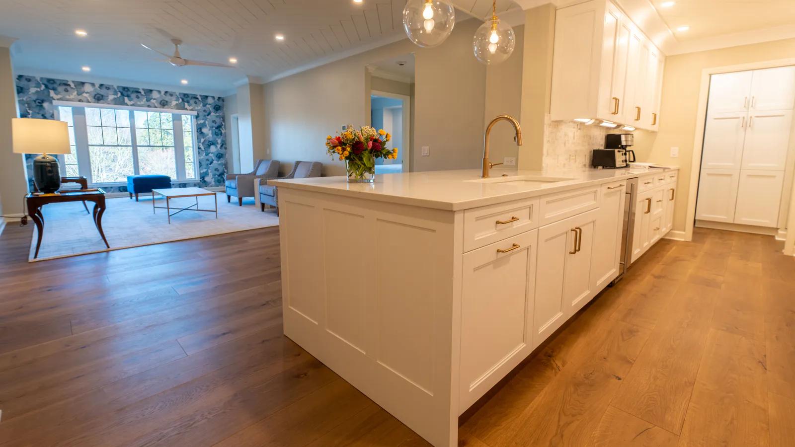 明亮住宅廚房中的白色中島與兩側木紋地板