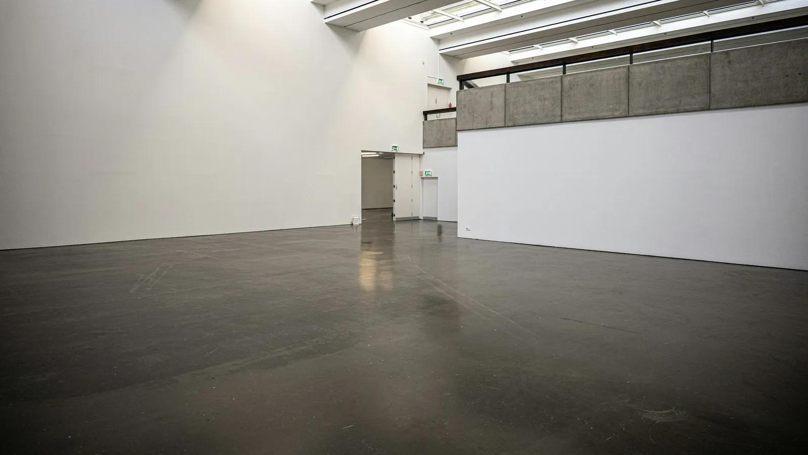 美術館展廳內的灰色拋光水泥地面,無接縫、帶低調光澤,天窗灑入自然光