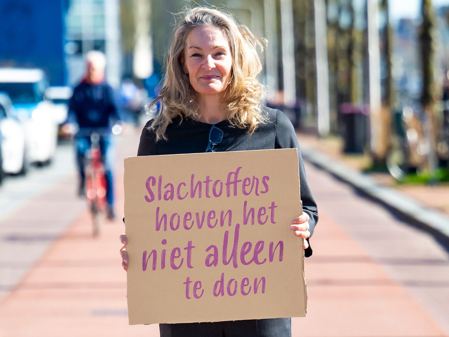 Saskia staat buiten met een bord met de quote: "slachtoffers hoeven het niet alleen te doen"