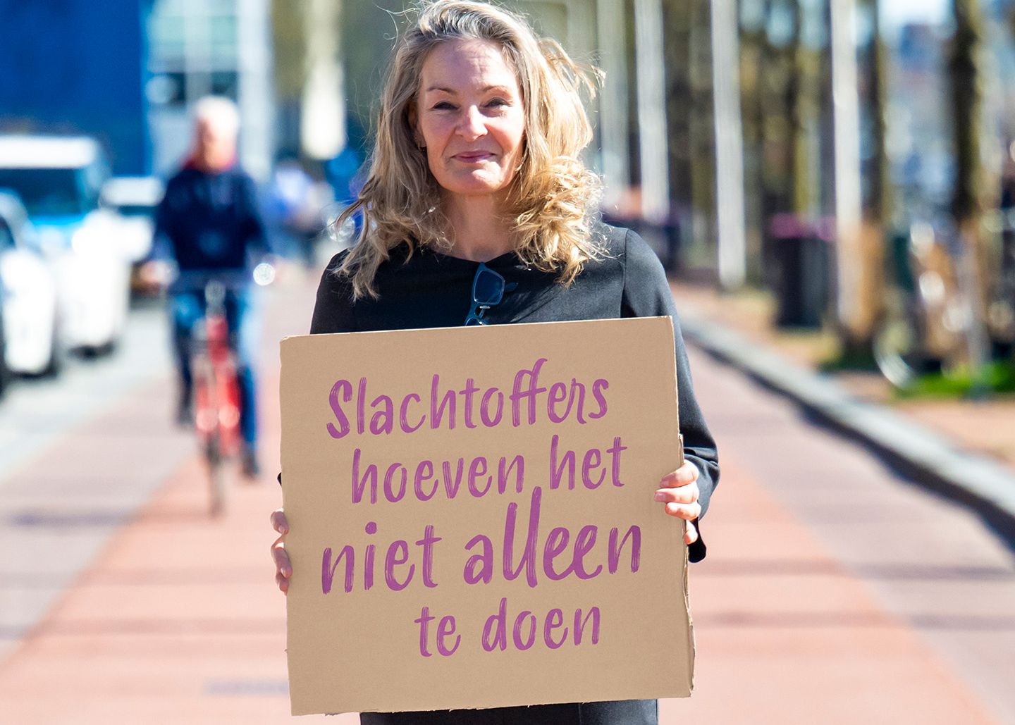 Saskia staat buiten met een bord met de quote: "slachtoffers hoeven het niet alleen te doen"