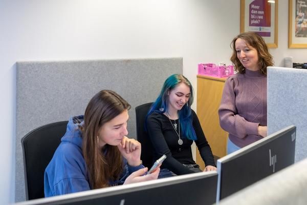Een teamleider in gesprek met twee jonge medewerkers.