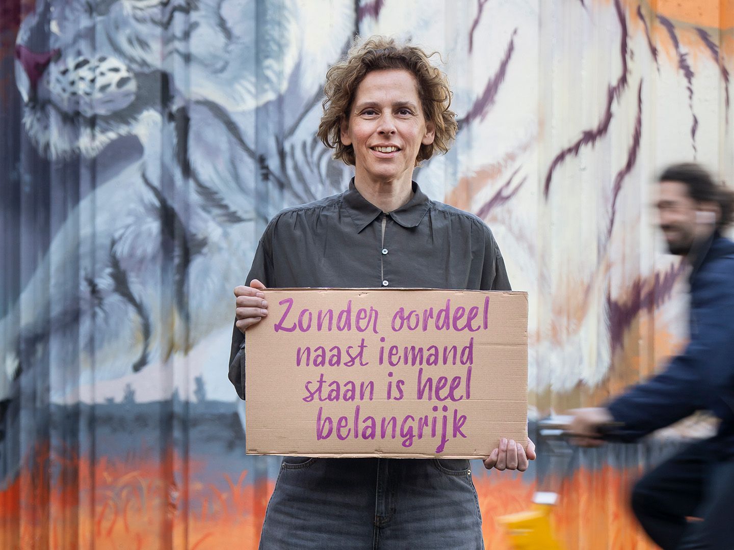 Carolien die buiten staat en een bord vasthoud met de Quote “Zonder oordeel naast iemand staan is heel belangrijk”