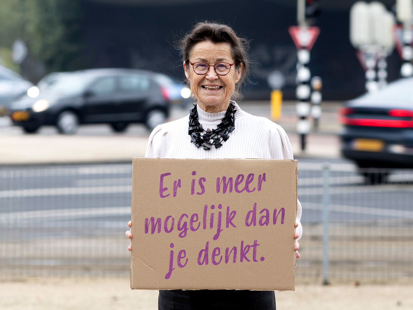 Vrijwilligster Anny staat buit met bord waarop staat: Er is mogelijk dan je denkt.