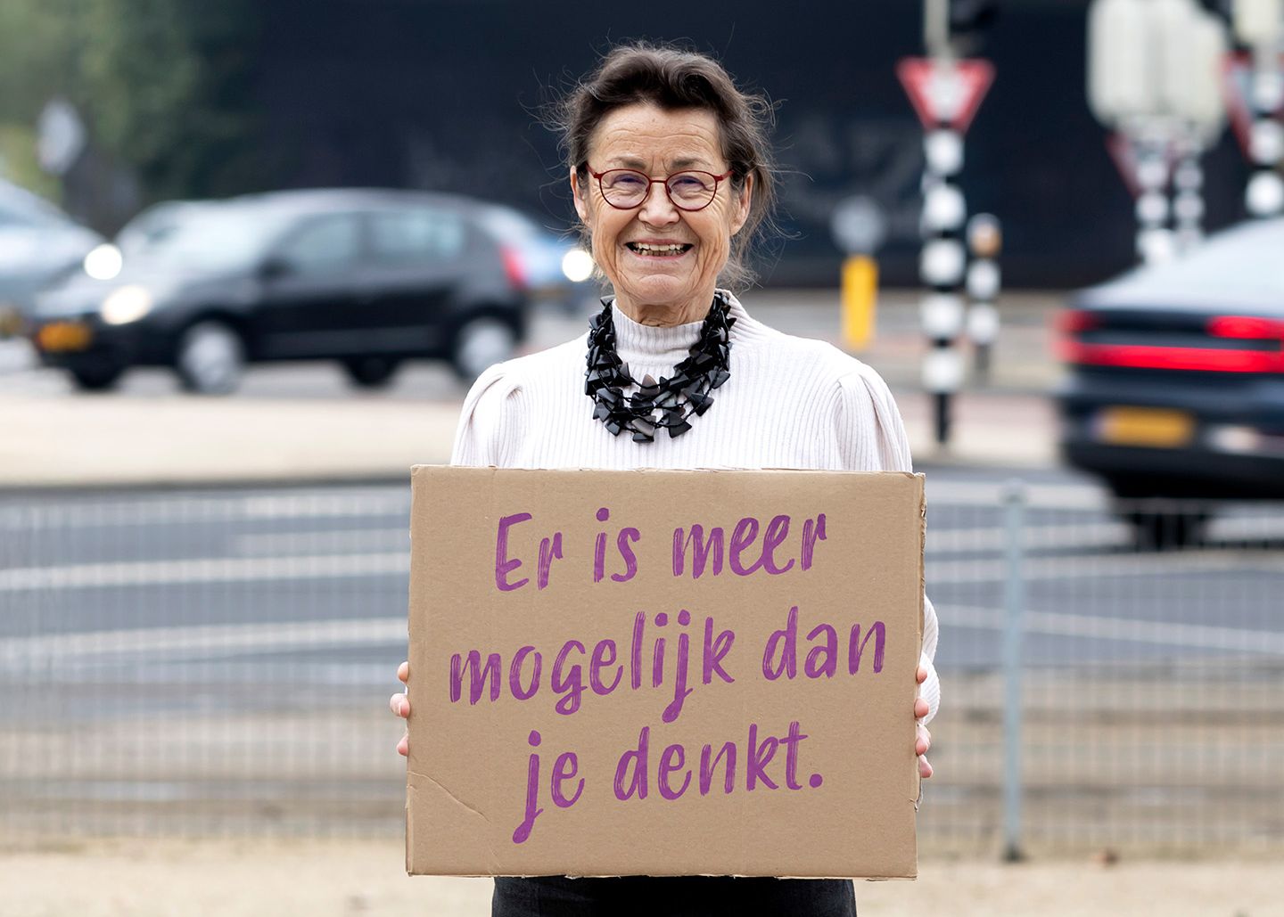 Vrijwilligster Anny staat buit met bord waarop staat: Er is mogelijk dan je denkt.