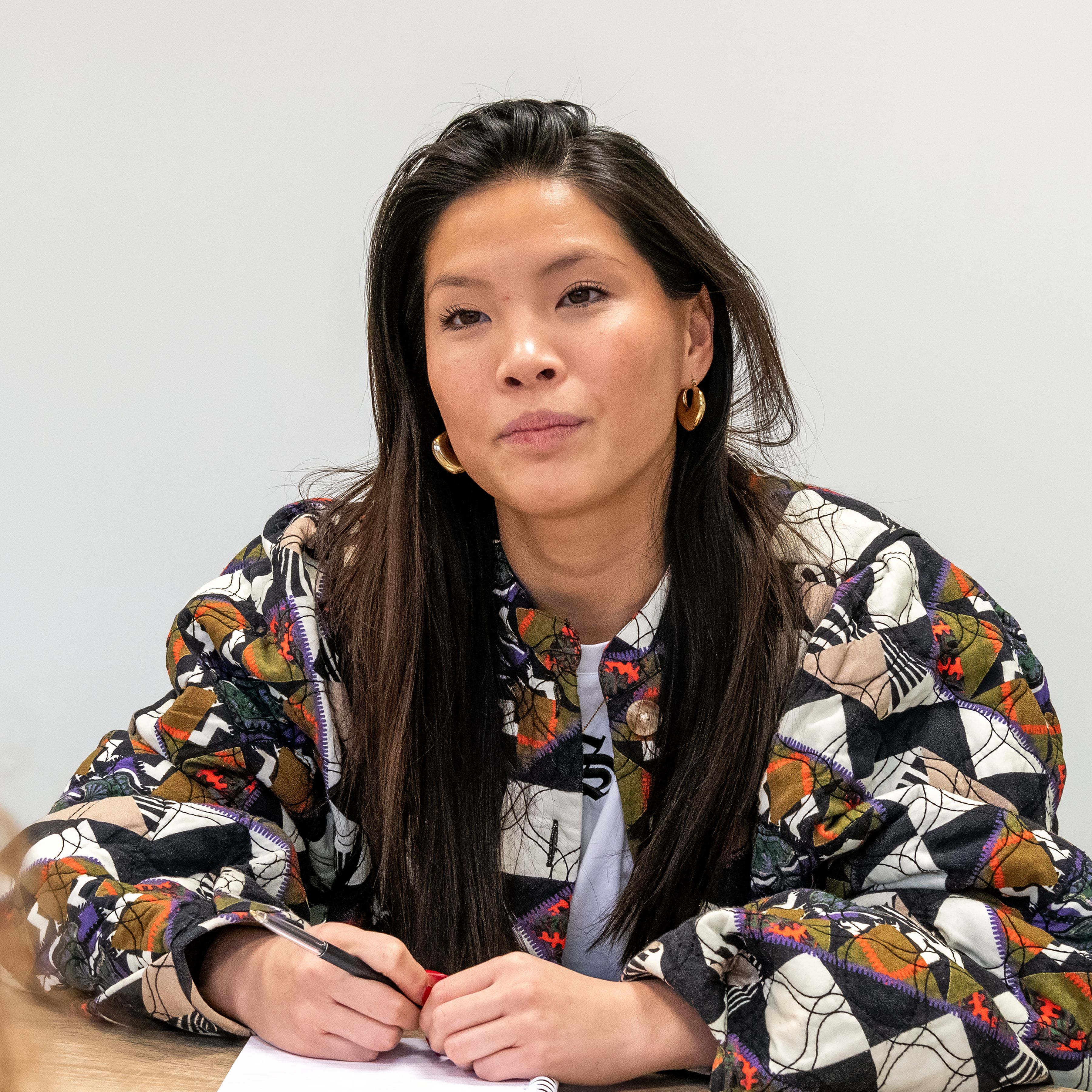 vrouw zit aan tafel en kijkt in camera