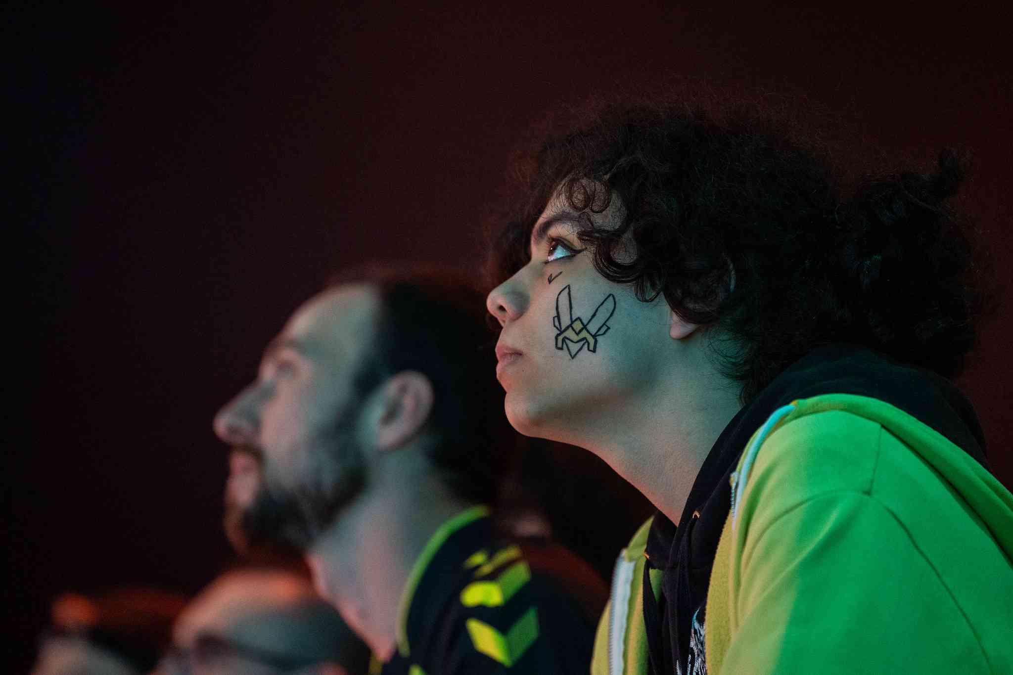 Vitality fans wearing team memorabilia and face paint watch the stage during a live game.
